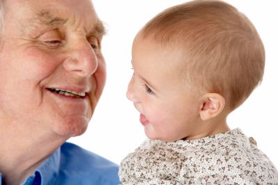 Portrait of grandfather and granddaughter, smiling at...