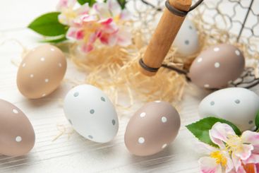 Easter eggs are decorating a white wooden table with...