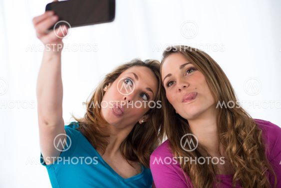 portrait of two beautiful girls making a funny selfie