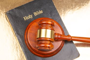 A traditional gavel sits on an open "Holy Bible" with...