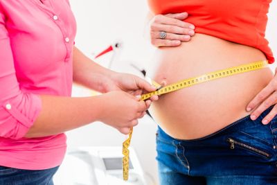 Standing pregnant women and midwife measuring...