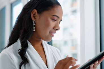 Business woman, tablet and reading in hallway at modern...