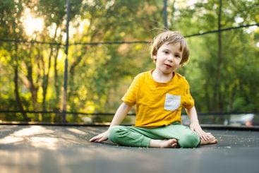 Little boy jumping on a trampoline in a backyard on warm...