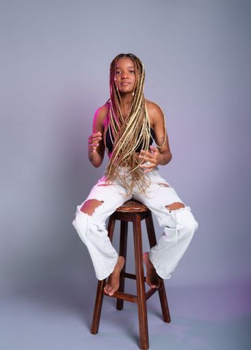 Brunette model with braids in her hair, wearing white...