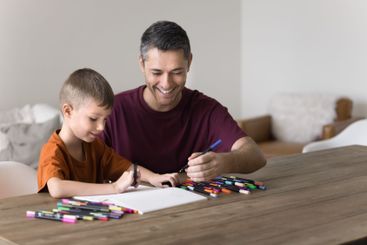 Father and little school-age drawing in album with...