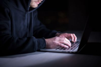 hacker using laptop computer while working in dark office