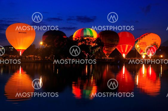 Hot air baloons flying in the evening sky near the lake