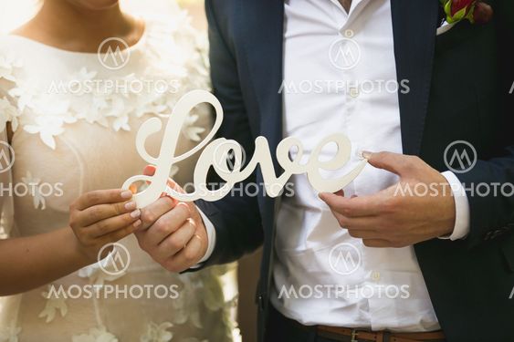 Closeup of bride and groom holding word Love