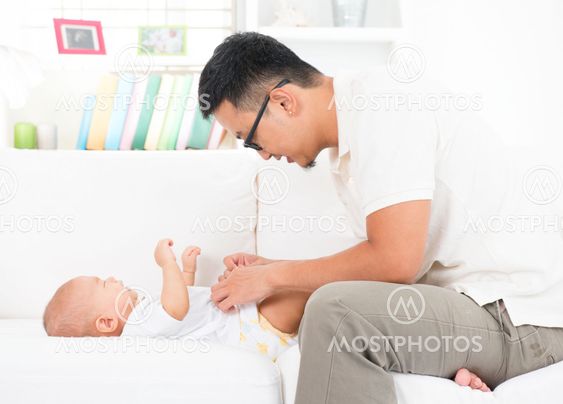Father changing diaper and clothes for baby.