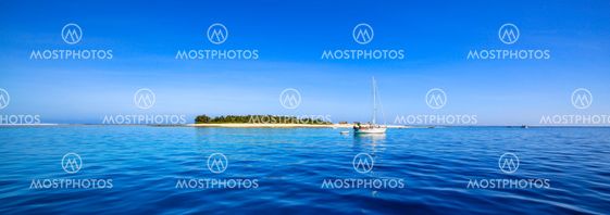 Boat and beautiful Fiji atoll island with white beach