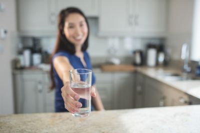 Young woman holding a glass of water in kitchen