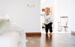 White blonde boy wearing home clothes laughing and playing