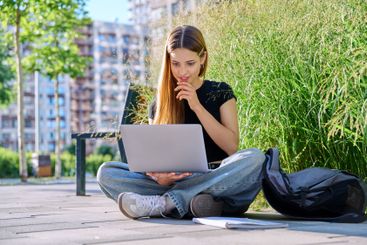 Young female college student using laptop computer outdoor