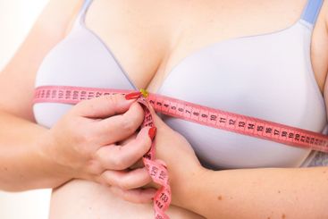 Woman measuring her chest breasts bust size