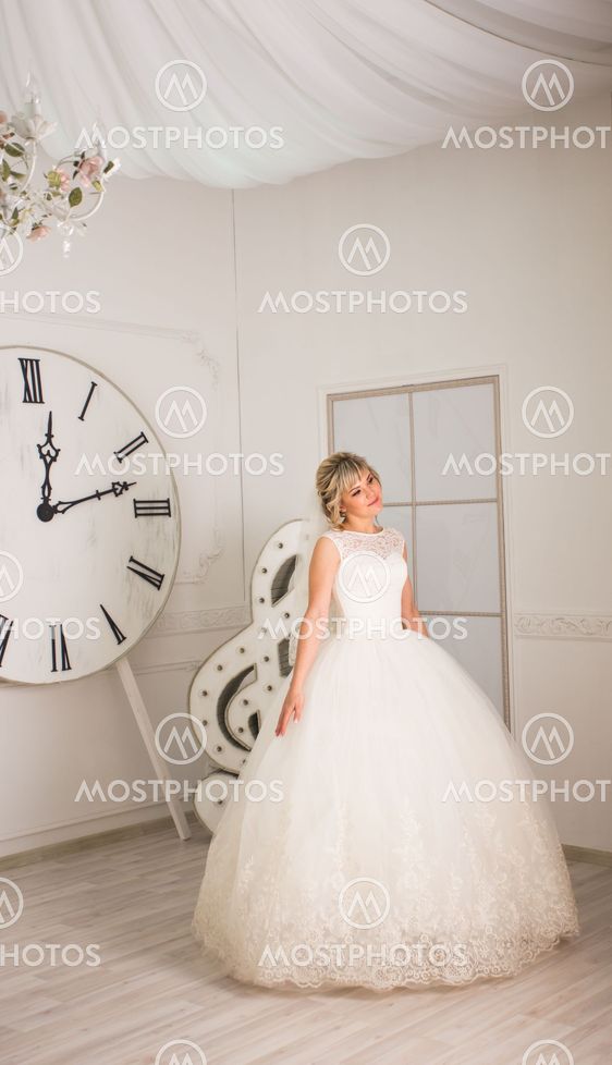 portrait of happy young woman in white wedding dress and...