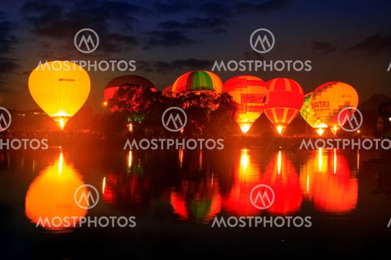 Hot air baloons flying in the evening sky near the lake