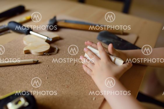Little boy learns work with tools. Kid make a wooden toy....