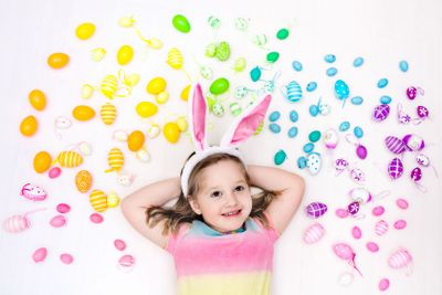 Child on Easter egg hunt. Pastel rainbow eggs.