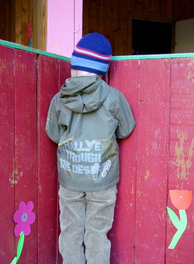 Boy stands in corner of veranda