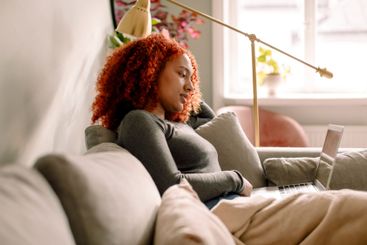 Side view of young businesswoman with laptop sitting on...