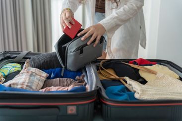 Woman packing suitcase on bed for a new journey packing...