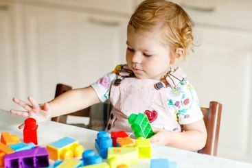 Adorable toddler girl with educational toys in nursery...