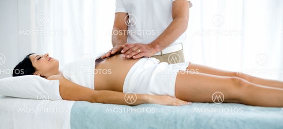 Pregnant woman receiving a stomach massage from masseur