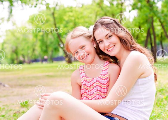 mother and daughter sitting together on the grass
