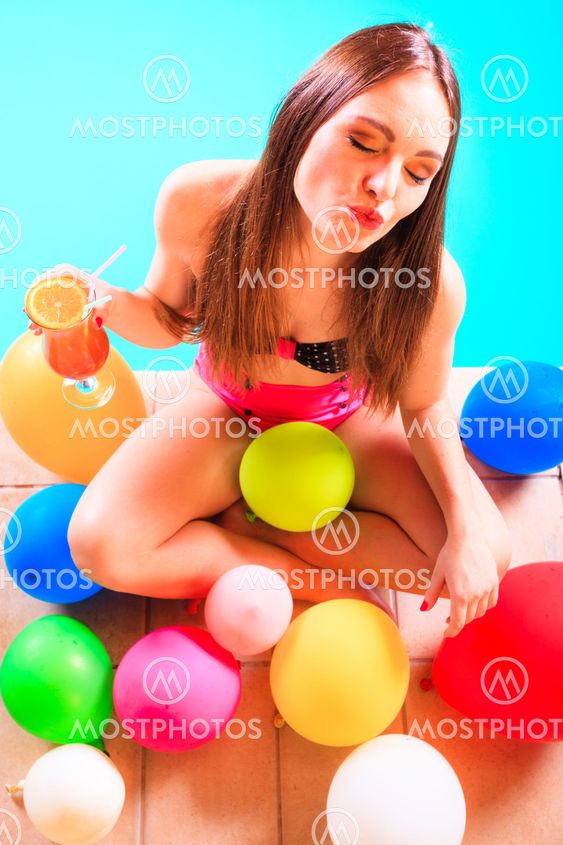 Happy woman with balloons and cocktail at poolside