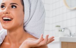 Cheerful woman with towel on head talking on telephone in...