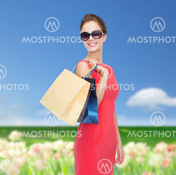 smiling woman in red dress with shopping bags