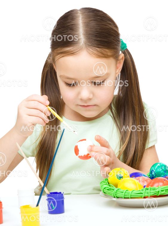 Little girl is painting eggs preparing for Easter