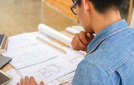 Architect and engineer analyzing blueprints at a work...