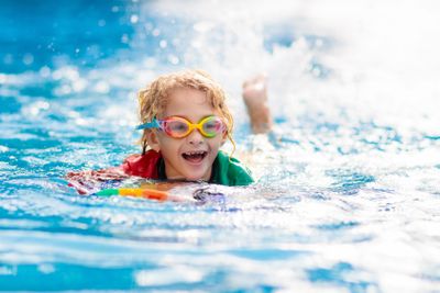 Child learning to swim. Kids in swimming pool.