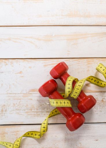 Fitness concept with dumbbells and measuring tape