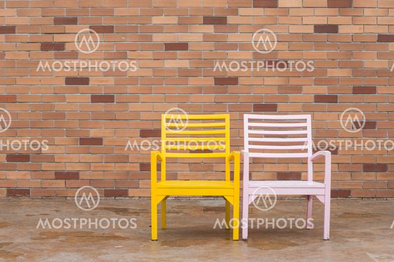 blue and yellow wooden chair and red brick wall