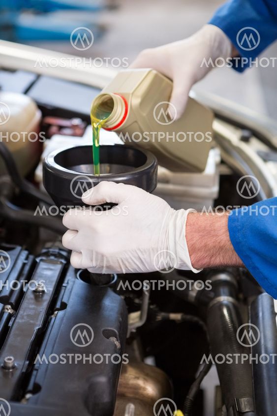Mechanic pouring oil into car
