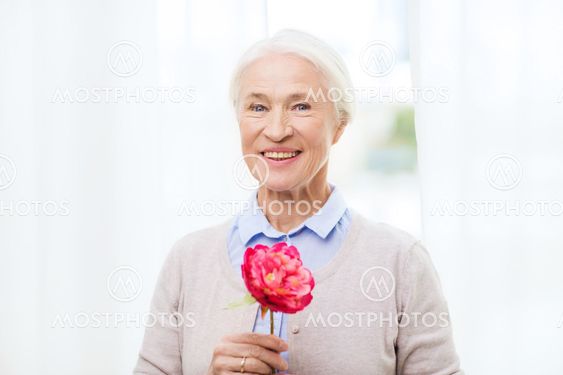 happy smiling senior woman with flower at home