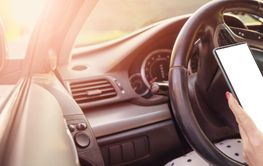 Woman sitting at the steering wheel and typing in...
