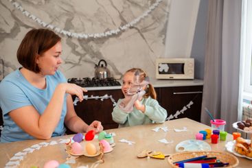Smiling mother and cute little girl play together with...