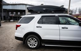 White Ford Explorer SUV with a roof box parked in an...