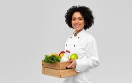happy smiling female chef with food in wooden box