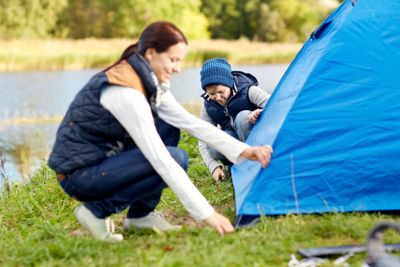 happy mother and son setting up tent outdoors