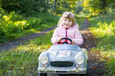 Little preschool girl driving big vintage toy car. Happy...