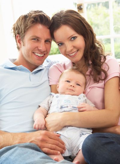 Parents Cuddling Newborn Baby Boy At Home