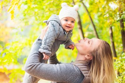 Mother and her little daughter play cuddling on autumn...