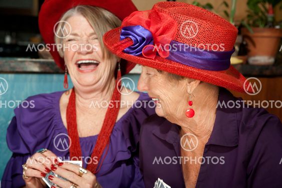 Ladies wearing red hats playing cards