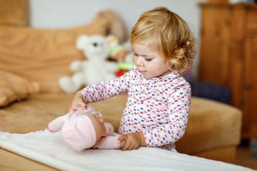 Adorable cute little toddler girl playing with doll....