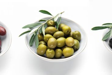 Black, green and kalamata olives with olive branches in...