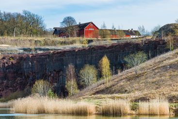Scenic view of a red barn atop rocky cliffs by a...